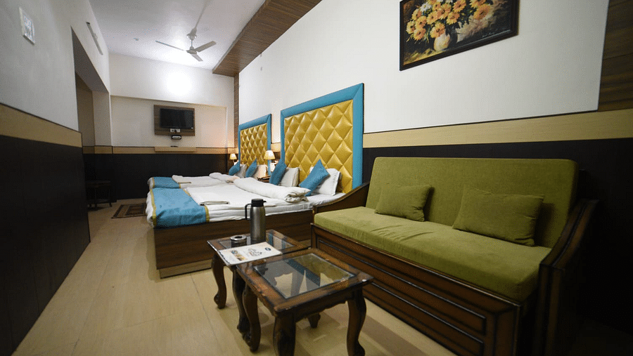 Four bed deluxe room with sofa and table on the side at Hotel Panchvati Inn, Joshimath