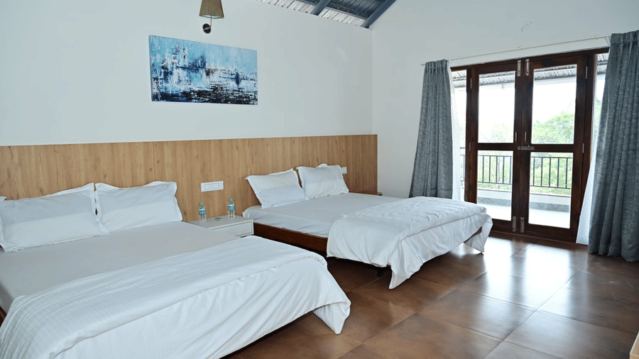 A room at Hilllock Vista Homestay by Aarika Resorts, with two beds, pillows, spreads, and a door leading to a balcony.
