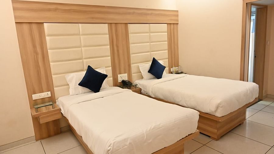 Bright hotel room at Rang Lords Inn, Bharuch, with two beds, a seating area, and a large, decorative headboard