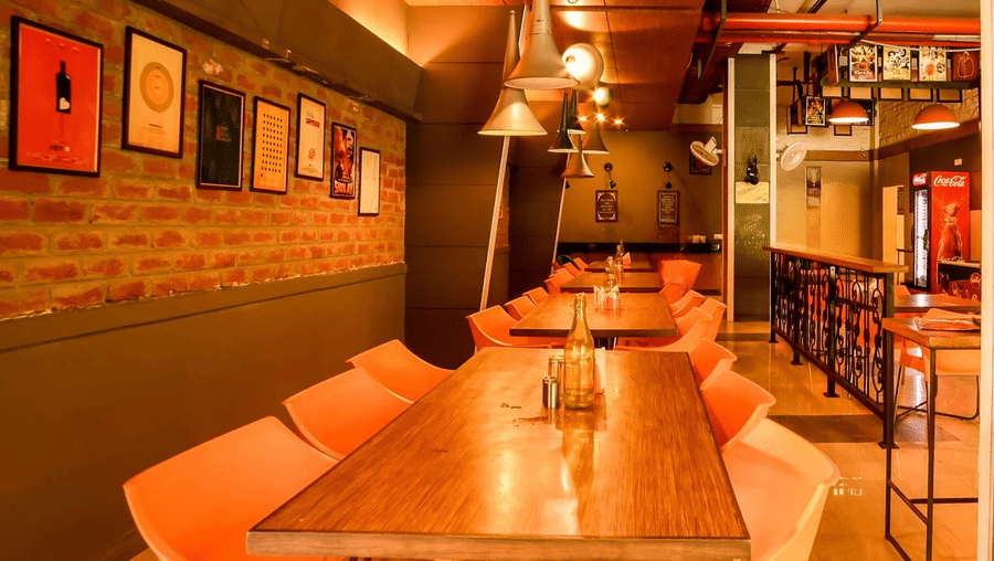 A contemporary hotel dining space with long wooden tables, modern chairs, and eclectic wall art creating a casual yet stylish ambiance.