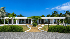 Premier Golf Vista Cottage exterior with palm-lined pathways and manicured gardens at Chariot Beach Resorts, set under a clear blue sky