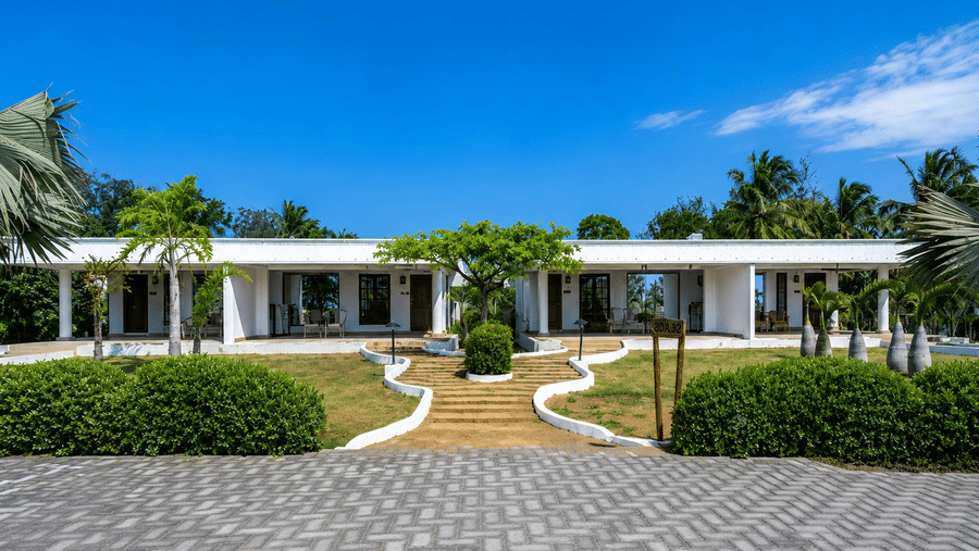 Premier Golf Vista Cottage exterior with palm-lined pathways and manicured gardens at Chariot Beach Resorts, set under a clear blue sky