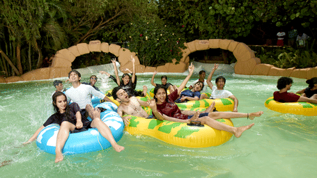 A group of people enjoying themselves on inflated tubes at Adventure Amazonia during daytime at Water Kingdom. Water Kingdom is one of the best places to visit for team & group outings in Mumbai.