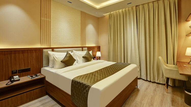 A double bed placed in the Deluxe Room with wooden flooring at Hotel 91 Privé, Gurugram, along with a workstation in the corner.
