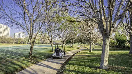 A golf cart on a tree-lined path with two people at Karma Chalets.