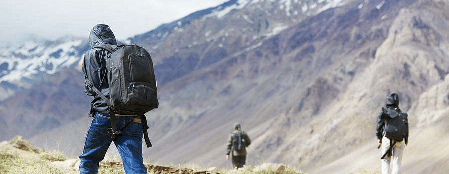Hiker exploring mountainous terrain with snow-capped peaks.