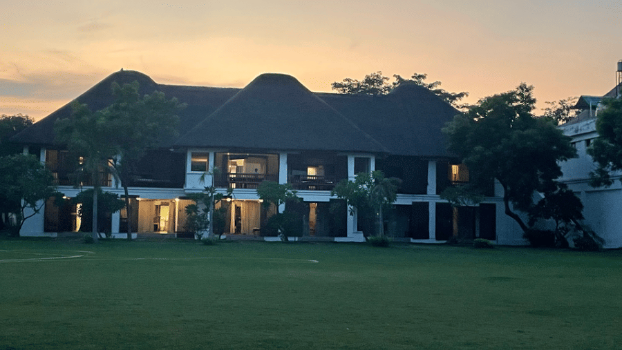 An exterior view of a 2-storey resort villa structure fronted by a large green lawn at dusk | Le Pondy