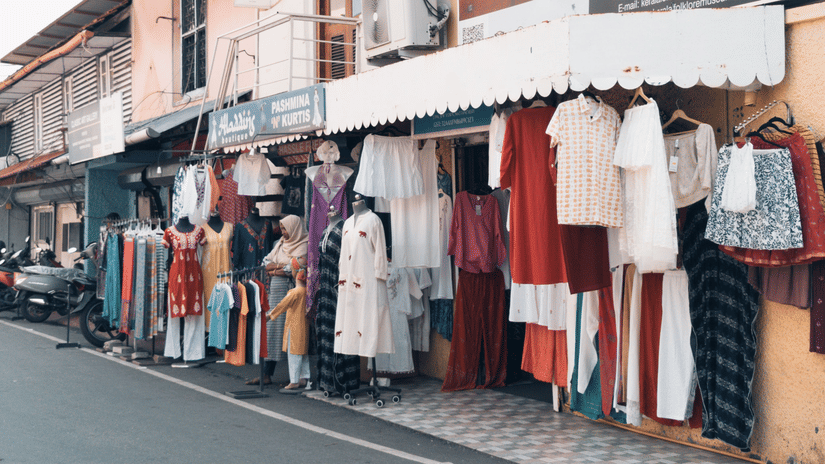 Local boutique shops showcasing clothing, handcrafted apparel, and fashion collections along a shopping street in Goa.