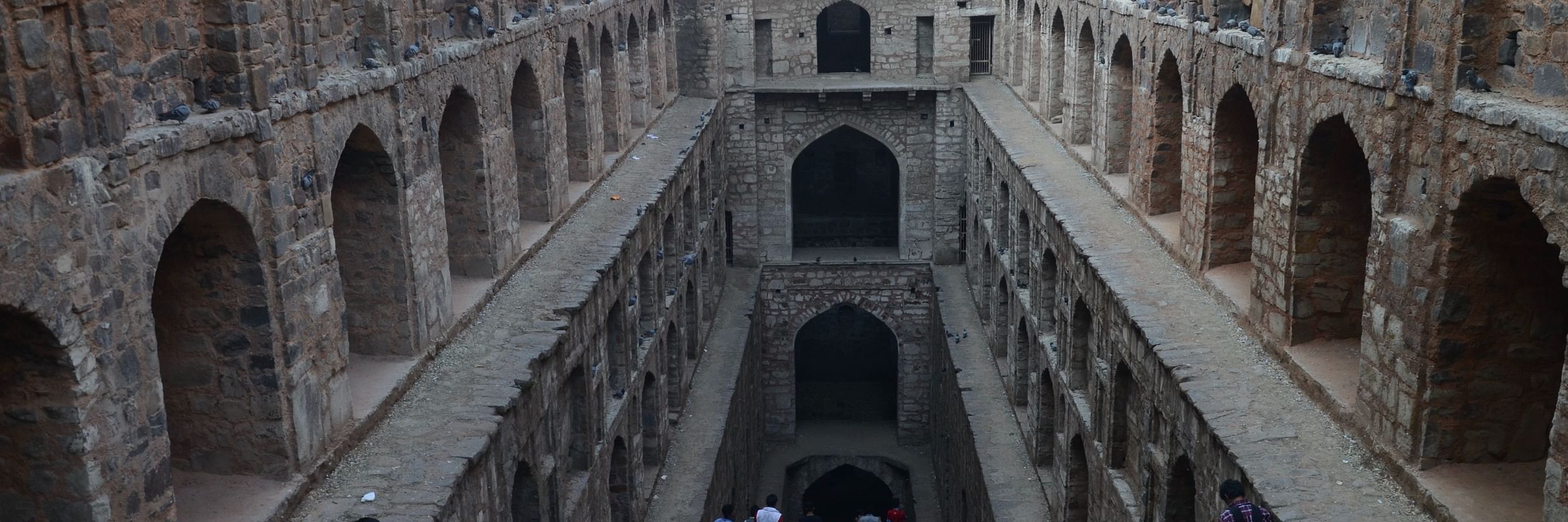 steps going downwards in a fort with people sitting on the steps