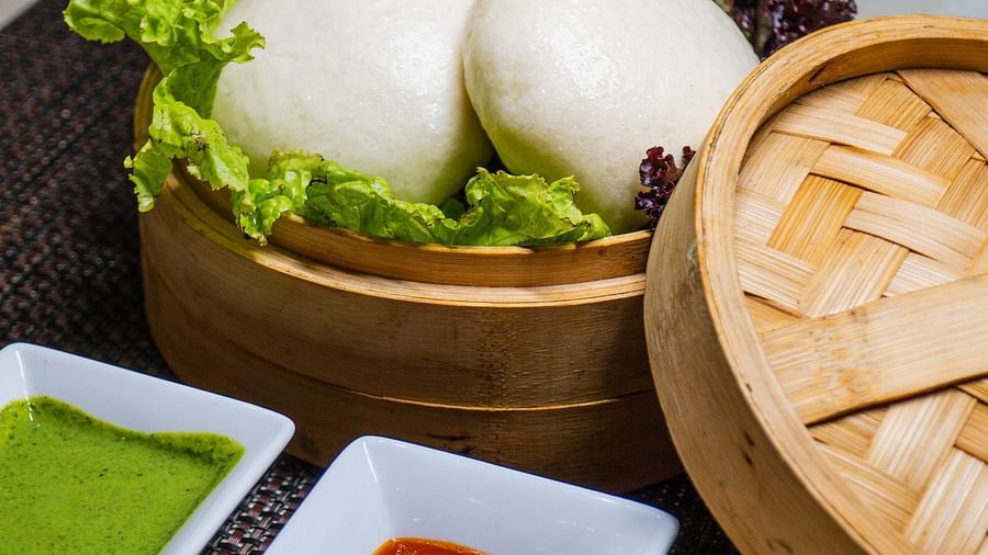 Steamed buns served in bamboo steamers with dipping sauces.