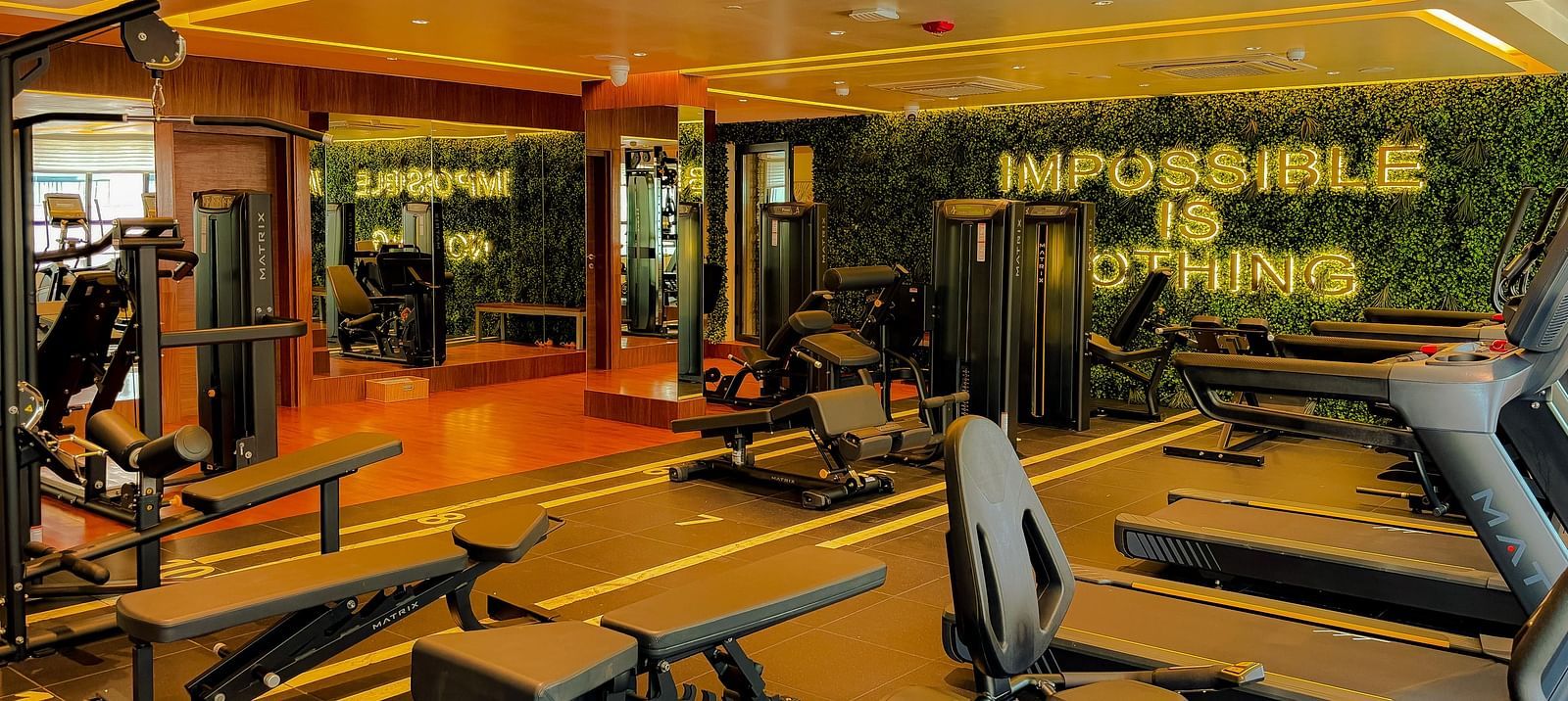 Fitness Center at KertelSuites, featuring modern gym equipment and the motivational quote Impossible is Nothing displayed