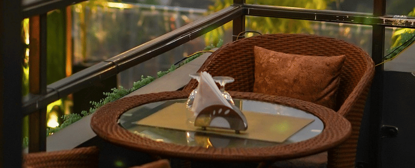 Two chairs facing each other on a terrace with warm lights besides it on a late evening.