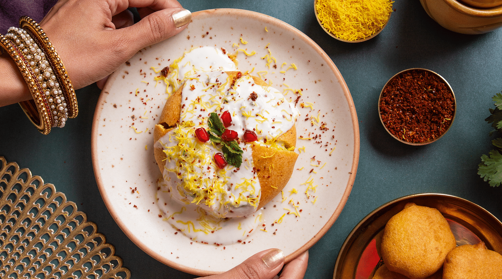 An image of a local fast food called fritters garnished with pomegranate, curd, and mint leaves 