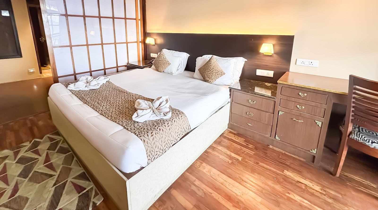 A bright bedroom with a neatly made bed, bedside tables, and wooden flooring at Avianna Hungry Jack, Gangtok.