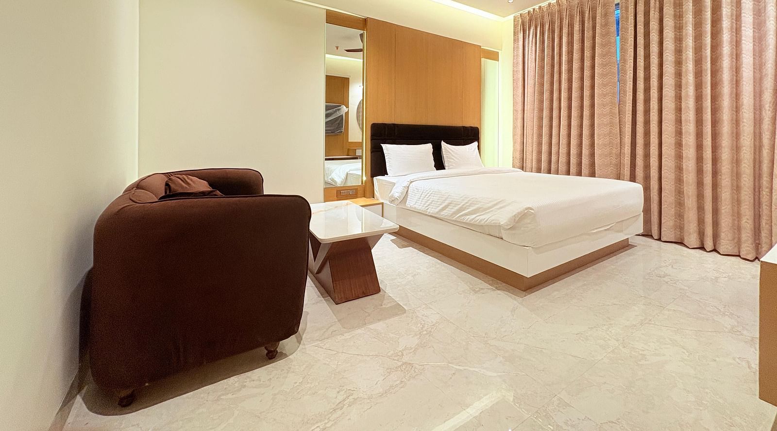 Bedroom with a huge cushioned sofa and a ceiling fan, at Hotel Mumbai House, Vashi.