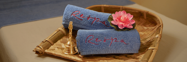 A massage table with folded towels and a small basket in a dimly lit room.