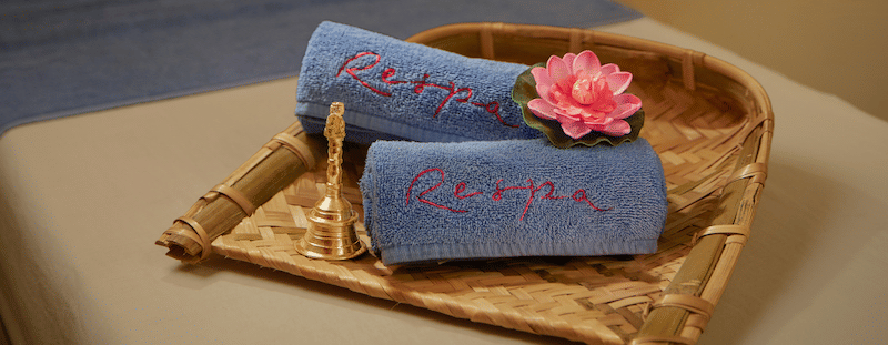 A massage table with folded towels and a small basket in a dimly lit room.