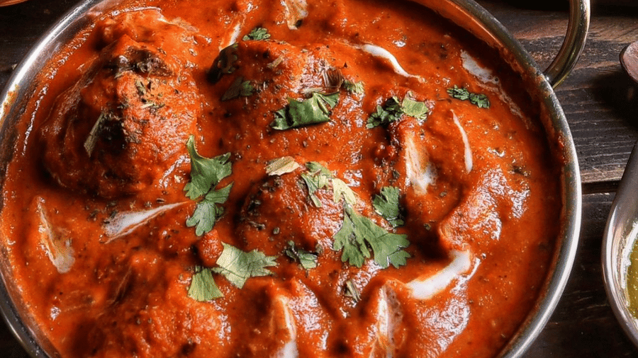 A metal bowl filled with meat curry is served alongside a basket of flatbread on a table at Amantra Shilpi Resort, Udaipur.