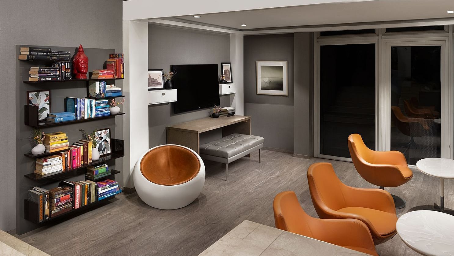 A spacious, modern multi-level living area at The Atara, Gurugram features an upper mezzanine level, a large bookshelf, a comfortable sofa, and a stylish armchair, creating an open design