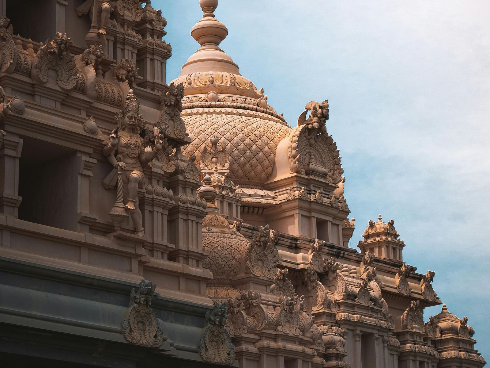 A  side angle view of the temple featuring intricate stone carvings on the top, showcasing detailed architectural design