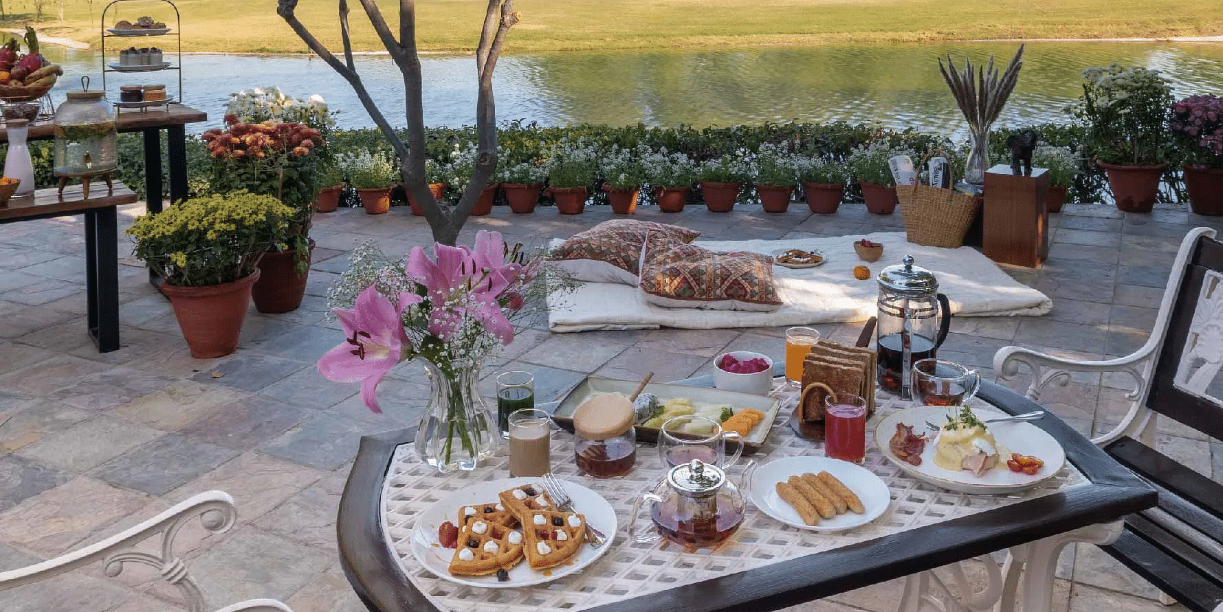 Outdoor dining table set with food and drinks near a lawn at Karma Chalets.