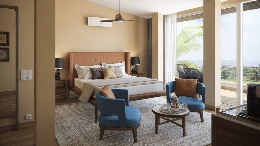 Suite with a bed, blue chairs, and a sliding glass door at Estherea Elite, Morjim.