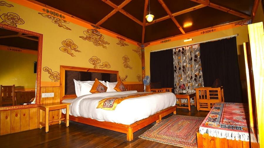 Premium Cottage at White Sands Resort, Ladakh, emphasising the king size bed, wooden furniture, and a rug.