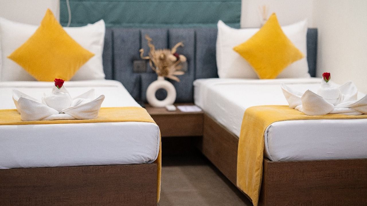 A twin room with two neatly made beds, accented with pillows and a decorative centrepiece on the bedside table at Hotel Kyzen Smartstays – Smart, Reliable, Kyzen