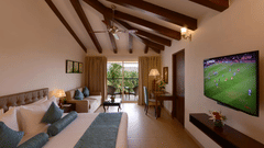 A wide angle view of a hotel room in Candolim featuring a king size bed, high ceilings, modern amenities, and a balcony with lush green views - Golden Tulip, Candolim, Goa