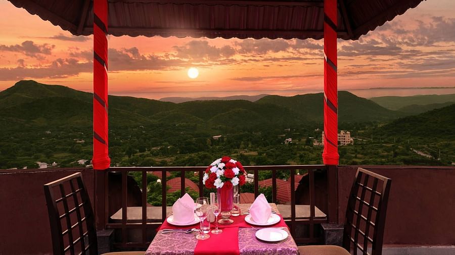 A table for 2 under a canopy with the sunset in the background at ananta tara-rooftop restaurant - The Ananta Udaipur