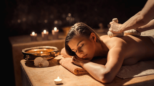 A woman receives a soothing herbal poultice massage in a candlelit spa setting, surrounded by warm tones and Ayurvedic wellness elements at YO1 Longevity & Health Resorts