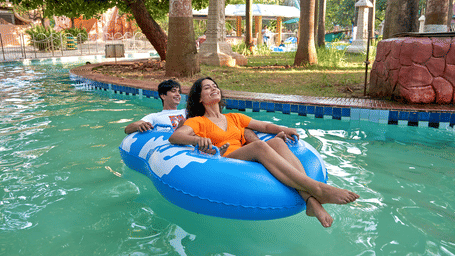 A man and a woman floating on a blue inflatable ring in a swimming pool | Water Kingdom