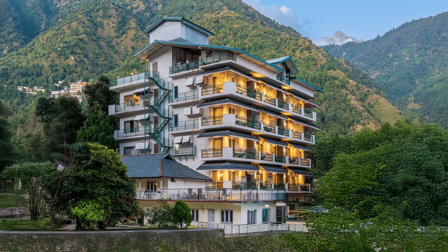 Facade of Quality Inn featuring a multi-storey building with balconies and a green fire escape staircase, set against a backdrop of hills and lush greenery.
