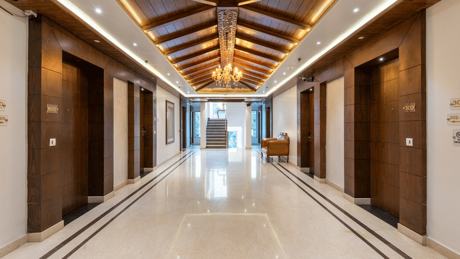 A well-lit corridor at Quality Inn, featuring a ambient lighting, polished floors and several doors.