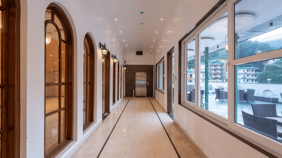 A brightly lit corridor at Quality Inn, with polished floors, arched windows and an outdoor terrace with seating.