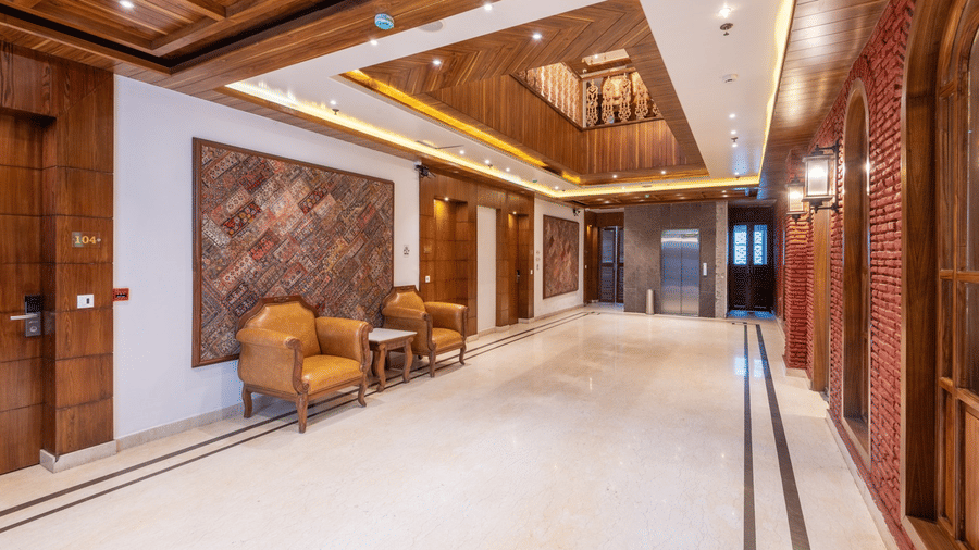 A hotel lobby at Quality Inn with wooden doors, cushioned armchairs, a mosaic pattern on the wall and ambient lighting.