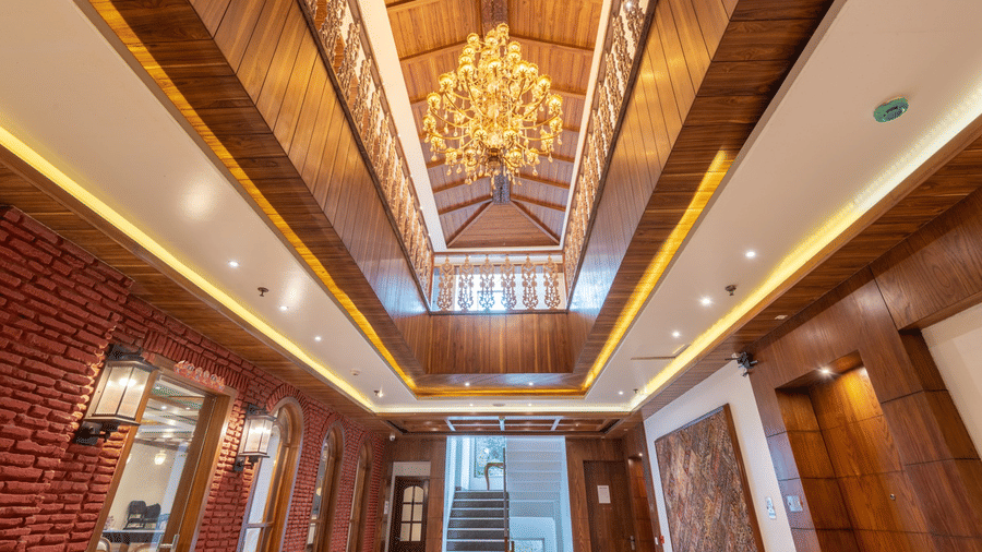A well-lit hotel lobby at Quality Inn with a grand chandelier, wooden furnished walls, and a wooden ceiling.