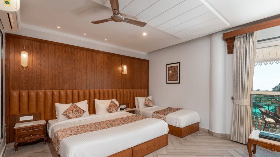 A hotel room at Quality Inn with access to a balcony, featuring a king size bed and a single bed, placed beside a wooden wall panel.