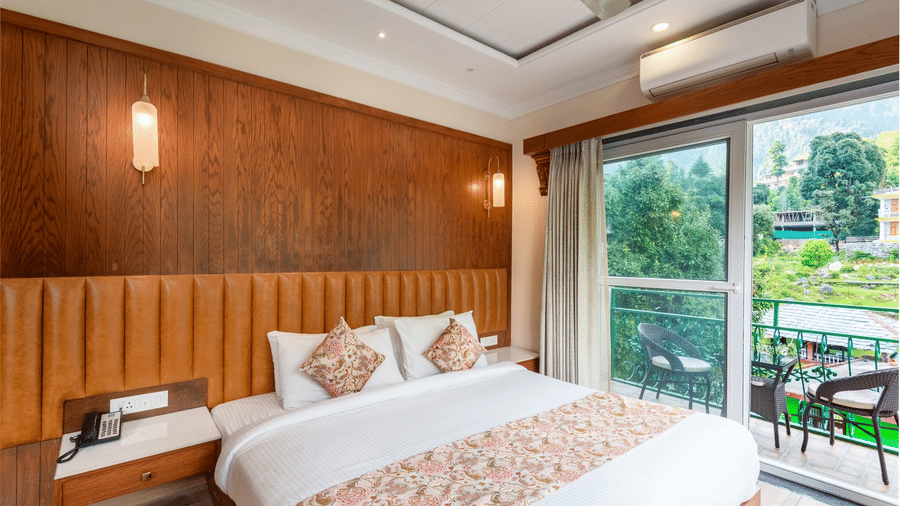  A family suite at Quality Inn with a king size bed, a wooden panelled wall with 2 lights, and a balcony with outdoor chairs.