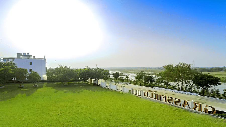An outdoor view of a large lawn under a bright sky with the sun shining intensely at Grassfield Riveria Resort.