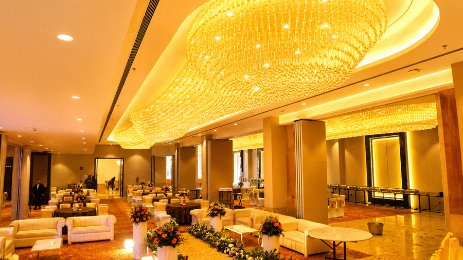 The grand banquet hall interior with a ceiling chandelier and dining arrangement at Ambrosia Sarovar Portico, Haridwar.