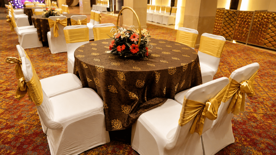 Round banquet table setup with a floral centrepiece and covered seating arrangement at Ambrosia Sarovar Portico, Haridwar.