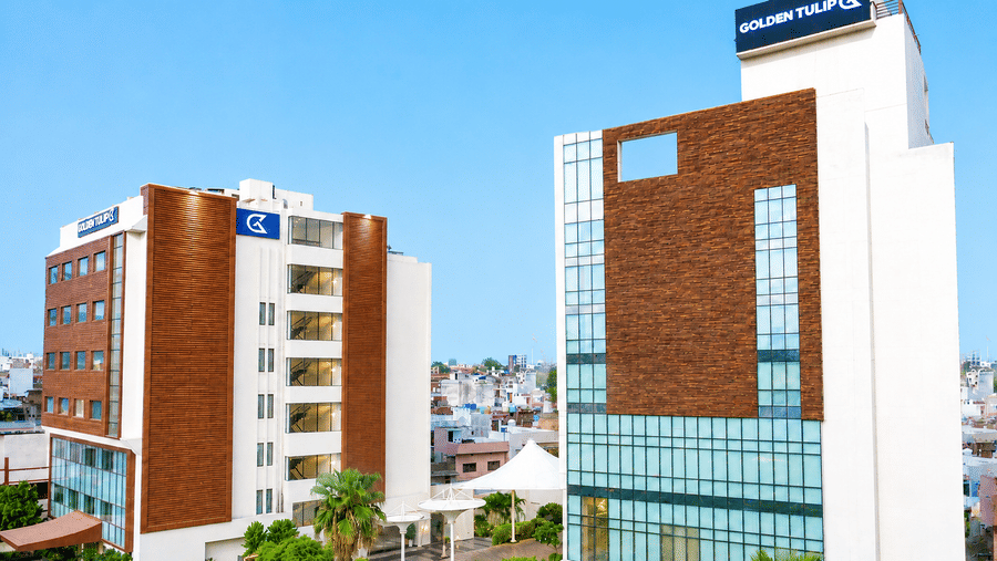 Exterior view of the two-building Golden Tulip Hotel Lucknow under a clear blue sky.