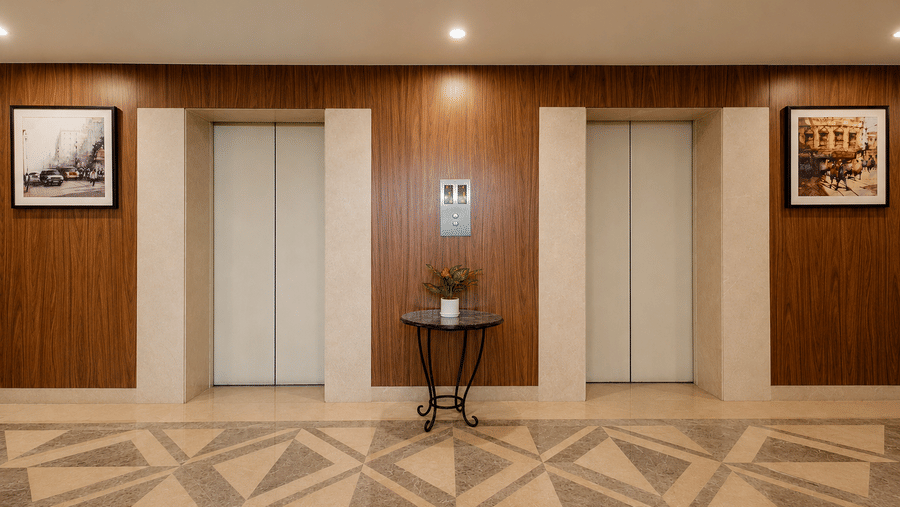 Hotel elevator lobby with wood-paneled walls, geometric marble flooring, and framed city artwork.