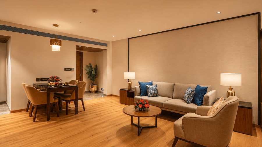 Spacious suite living area at Pride Premier Pune with sofas, armchairs, dining table and warm lighting.