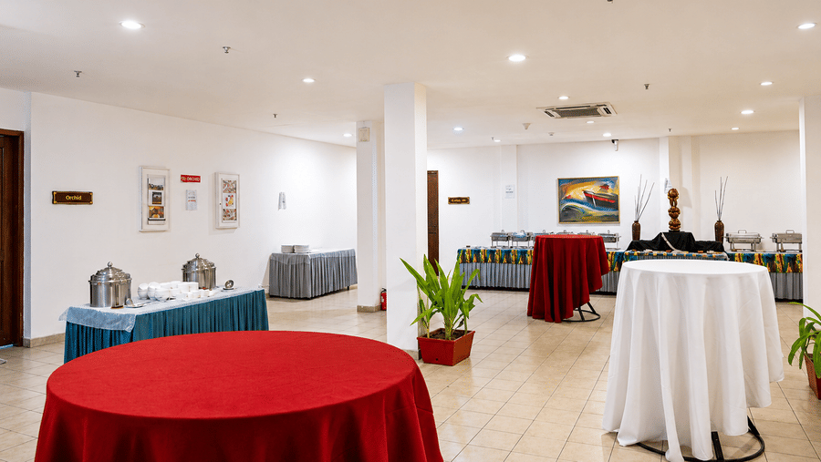 Pre Function Area featuring round tables in red and blue linens at Chariot Beach Resort, offering a versatile space for events.