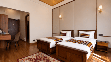 Premium Twin room at Summit Rungkhung Village Resort - The Signature Collection contains two single beds, side tables, wall lamps, a floor rug, wooden flooring, and a desk in the background.