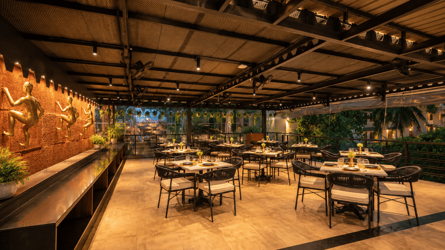 A warm open-air restaurant area at BluSalzz Collection - Casa Onze, Arpora with table seating.