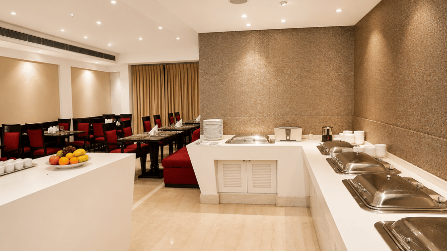 Restaurant buffet counter with a white display unit, red booth seating and cream-toned walls with warm recessed lighting spread overhead.
