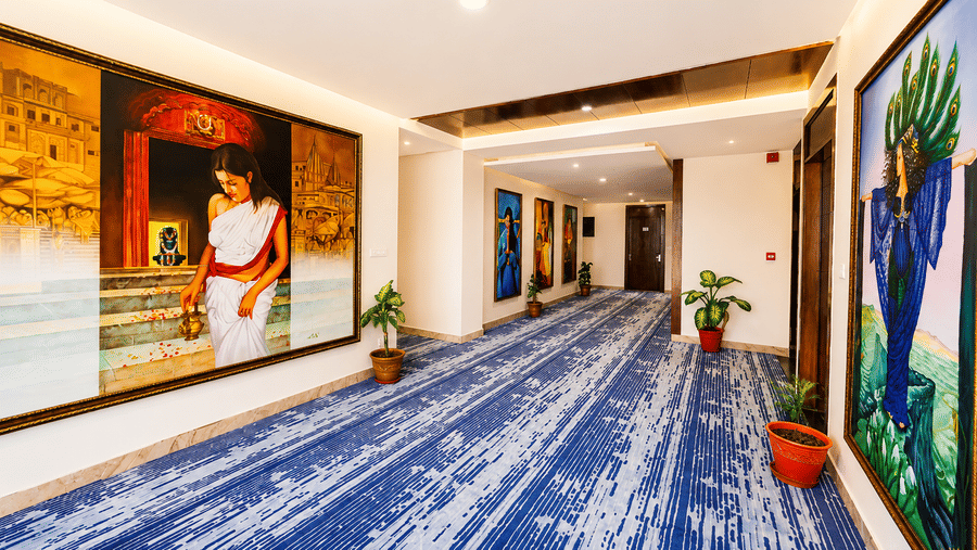 Hotel corridor with blue patterned carpet and large framed wall artwork at Eastlynn Resort, Rishikesh.